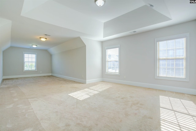 additional living space featuring lofted ceiling, visible vents, baseboards, and light colored carpet