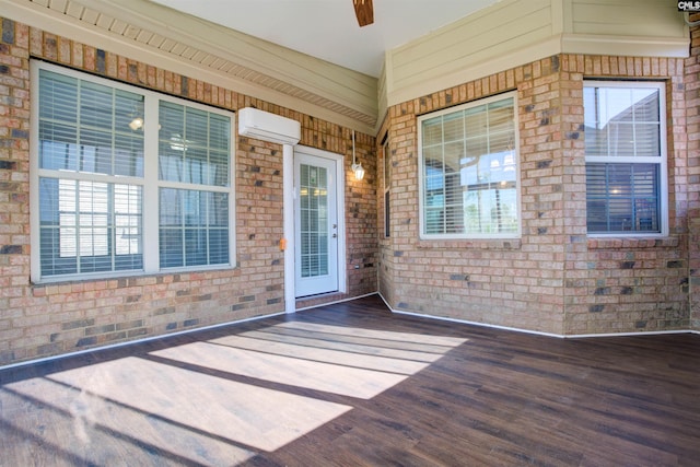 property entrance featuring a deck, brick siding, and a wall unit AC