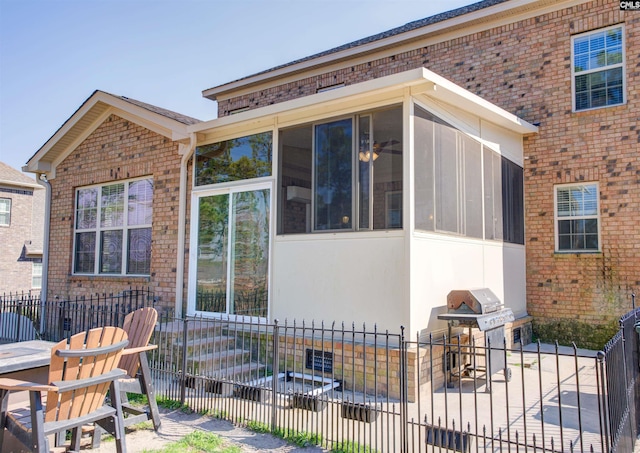 view of side of home featuring brick siding, fence, and a sunroom