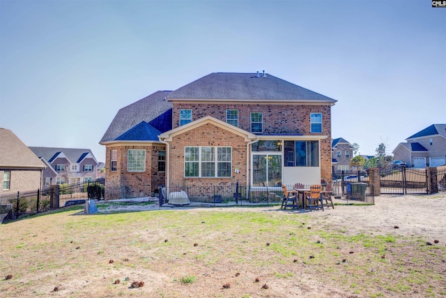 rear view of property with a yard, brick siding, roof with shingles, and a fenced backyard