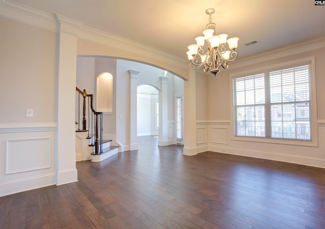 spare room with arched walkways, a decorative wall, dark wood-style flooring, visible vents, and stairway