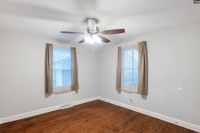 unfurnished room featuring baseboards, a textured ceiling, visible vents, and dark wood-type flooring