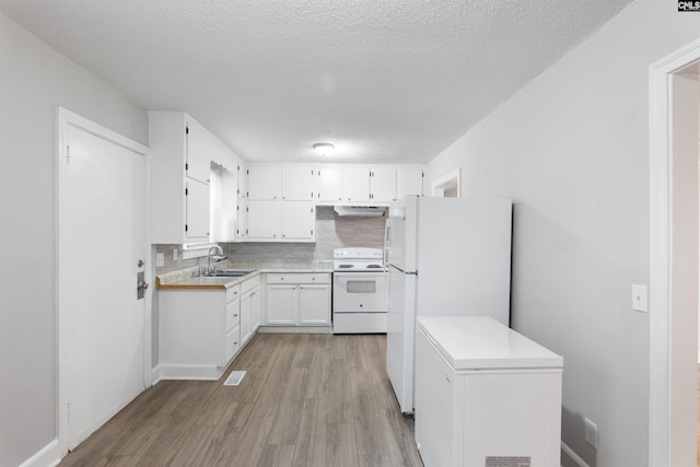 kitchen with under cabinet range hood, white appliances, a sink, light wood-style floors, and backsplash