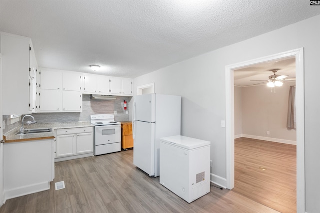 kitchen featuring light countertops, decorative backsplash, light wood-type flooring, white appliances, and under cabinet range hood