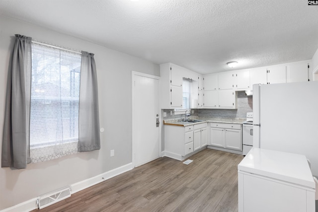 kitchen featuring white appliances, a sink, visible vents, light countertops, and light wood-type flooring