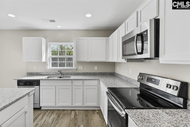 kitchen with visible vents, light wood-style flooring, appliances with stainless steel finishes, white cabinets, and a sink