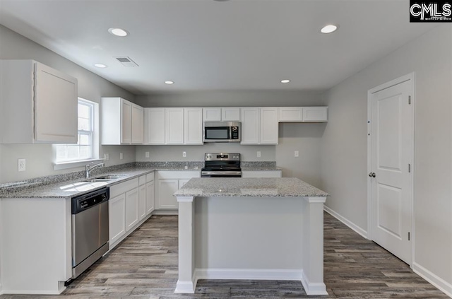 kitchen with stainless steel appliances, a sink, visible vents, white cabinetry, and light stone countertops