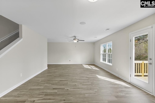 spare room with baseboards, visible vents, a ceiling fan, and wood finished floors