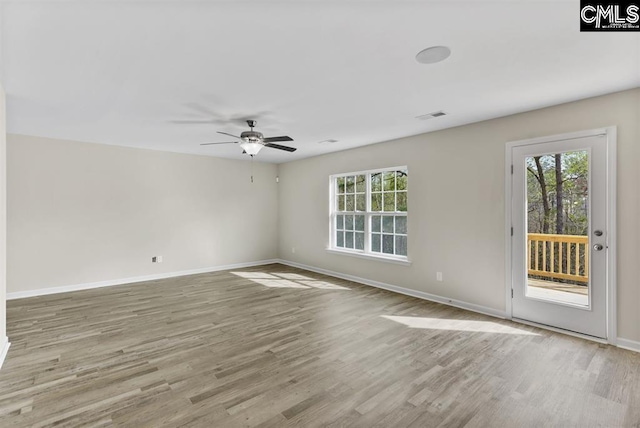 spare room featuring baseboards, plenty of natural light, visible vents, and wood finished floors