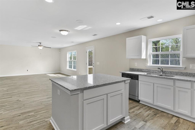 kitchen featuring visible vents, a center island, light wood-type flooring, stainless steel dishwasher, and a sink