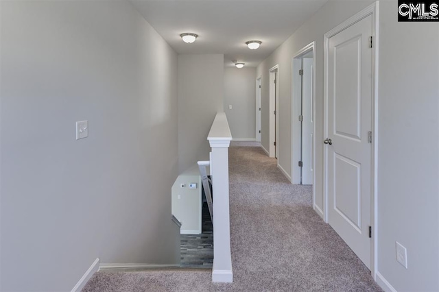 corridor featuring carpet floors, baseboards, and an upstairs landing