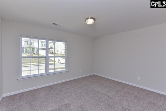 spare room with carpet flooring, visible vents, and baseboards