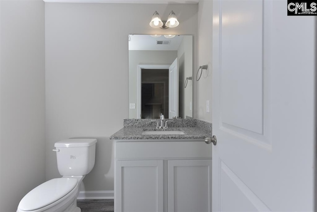 half bathroom featuring baseboards, visible vents, vanity, and toilet