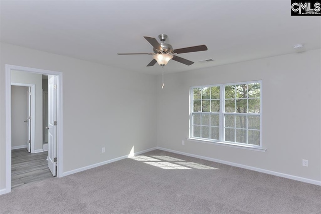 carpeted spare room with a ceiling fan, visible vents, and baseboards