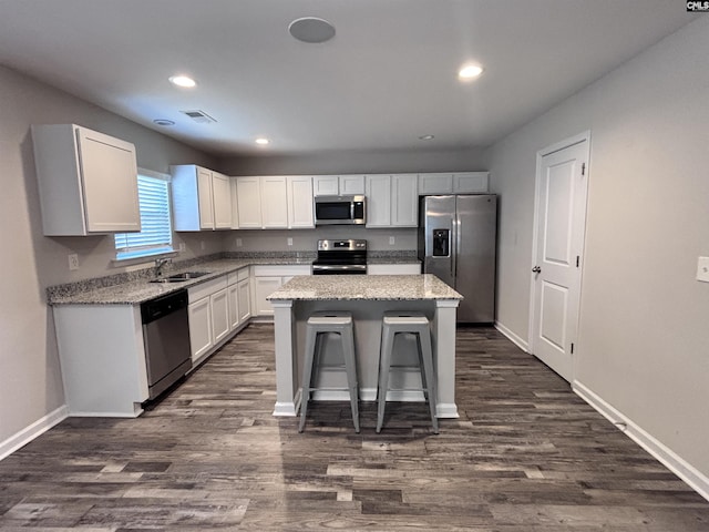 kitchen featuring visible vents, appliances with stainless steel finishes, a center island, white cabinetry, and a sink