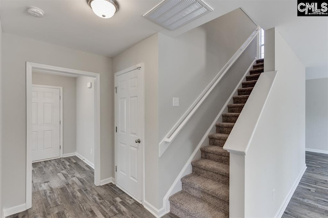 stairway featuring baseboards, visible vents, and wood finished floors