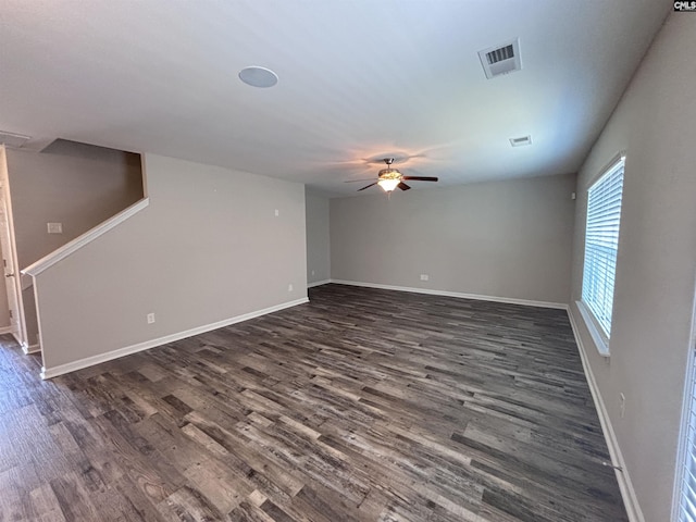 empty room with baseboards, ceiling fan, visible vents, and dark wood-style flooring