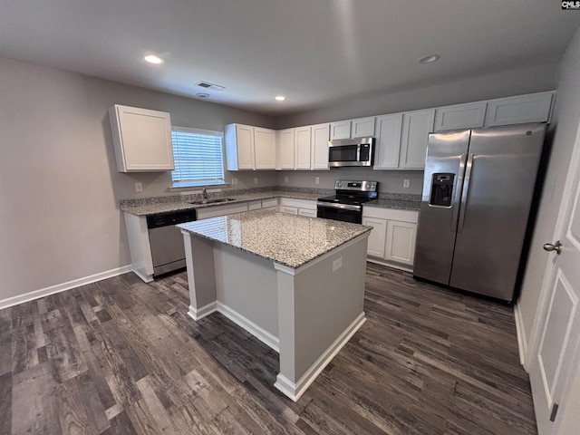 kitchen with appliances with stainless steel finishes, dark wood finished floors, visible vents, and a kitchen island