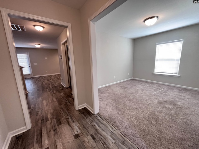 unfurnished room featuring visible vents, baseboards, and dark colored carpet