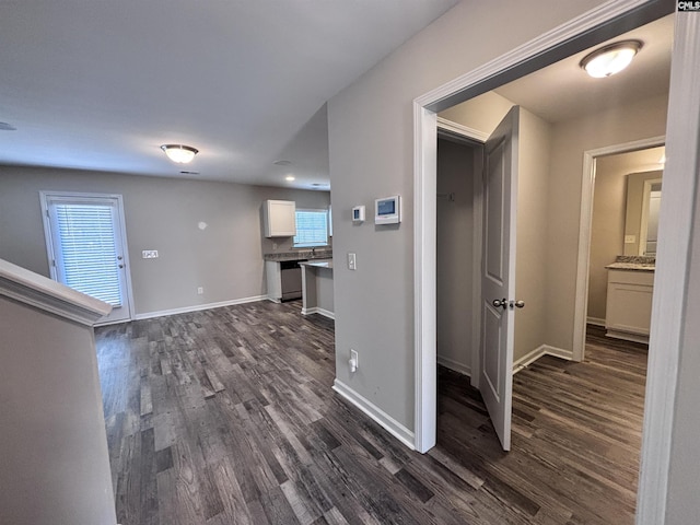 hall with dark wood-style flooring and baseboards