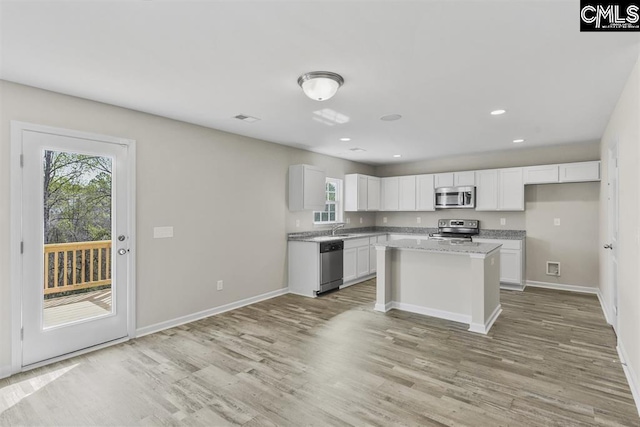 kitchen with baseboards, appliances with stainless steel finishes, a sink, and light wood-style floors