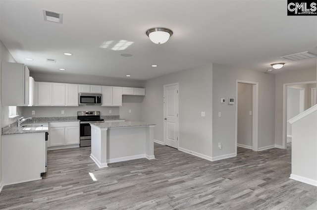 kitchen featuring white cabinets, appliances with stainless steel finishes, light wood-style flooring, and baseboards