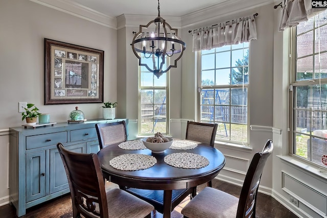 dining space with ornamental molding, a chandelier, and dark wood finished floors