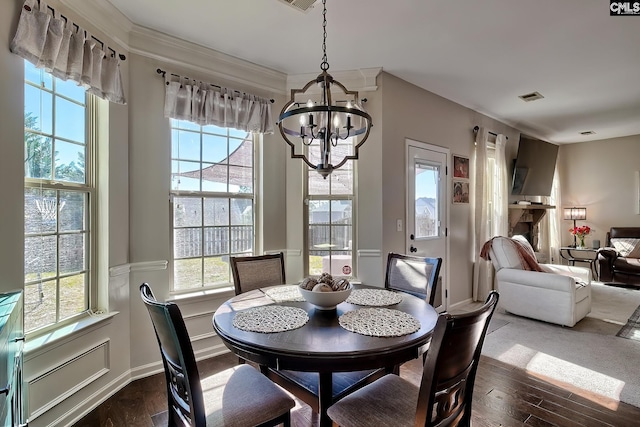 dining room with dark wood-type flooring, plenty of natural light, visible vents, and an inviting chandelier