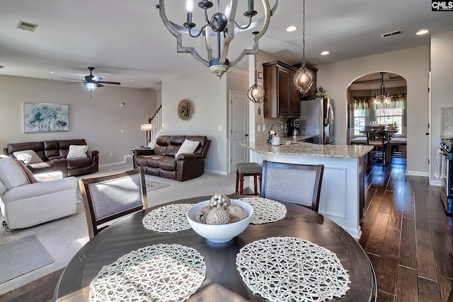 dining room featuring arched walkways, dark wood-style flooring, visible vents, and ceiling fan with notable chandelier