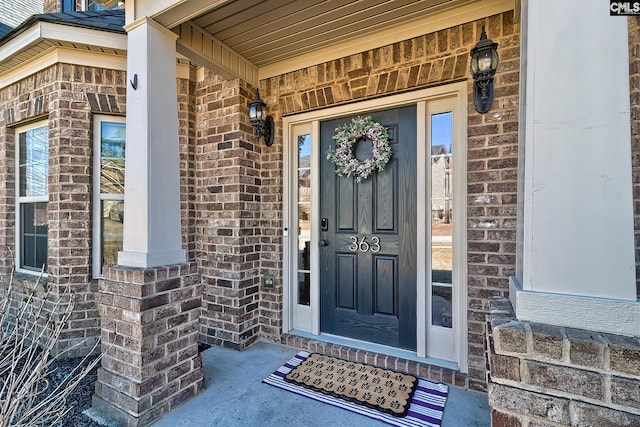 doorway to property with covered porch and brick siding