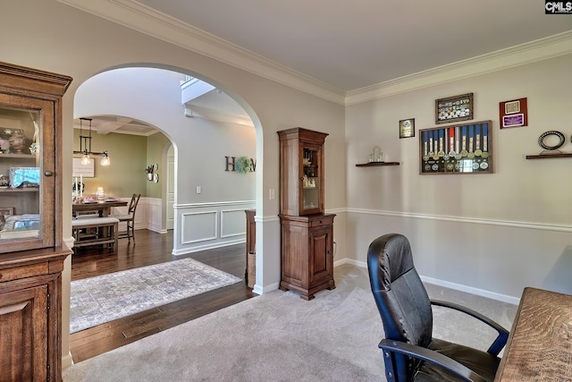 home office featuring arched walkways, a decorative wall, wood finished floors, wainscoting, and crown molding