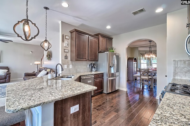 kitchen featuring arched walkways, stainless steel appliances, visible vents, dark wood-type flooring, and a sink