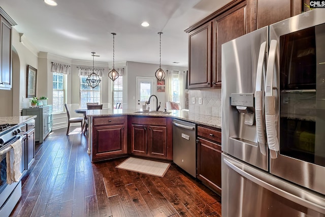 kitchen featuring decorative backsplash, dark wood finished floors, appliances with stainless steel finishes, a peninsula, and a sink