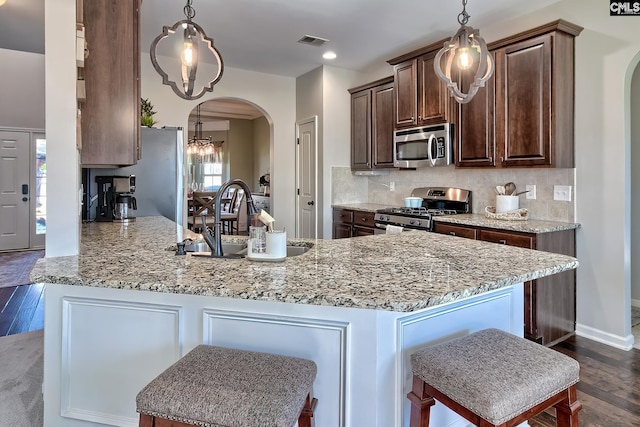 kitchen featuring arched walkways, a sink, visible vents, appliances with stainless steel finishes, and tasteful backsplash