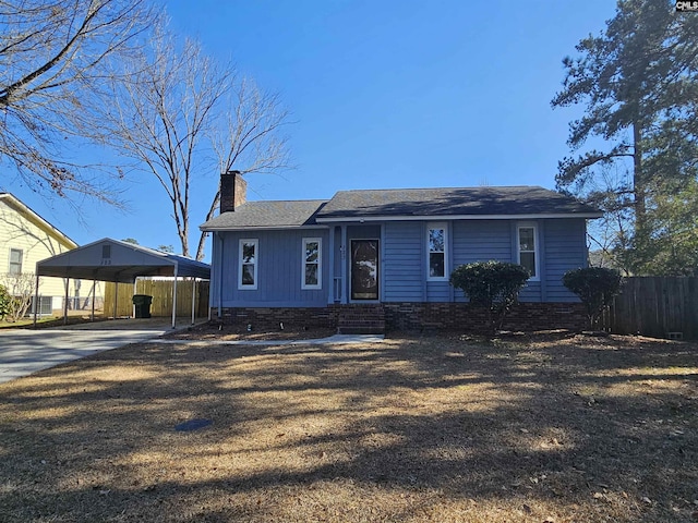 view of front of home with a carport, a chimney, fence, and driveway