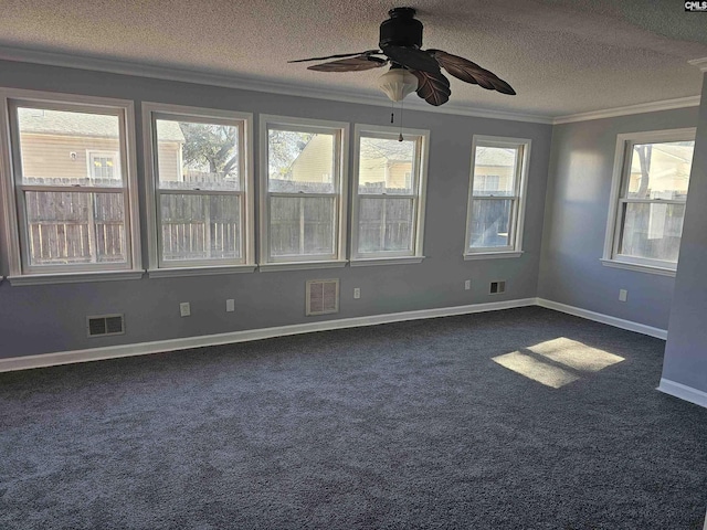 empty room featuring a textured ceiling, visible vents, dark carpet, and crown molding