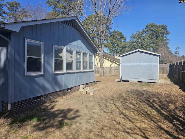 view of property exterior featuring crawl space, a fenced backyard, and an outdoor structure