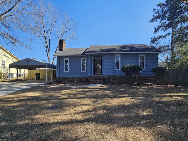 view of front of house featuring driveway, a detached carport, fence, and a chimney