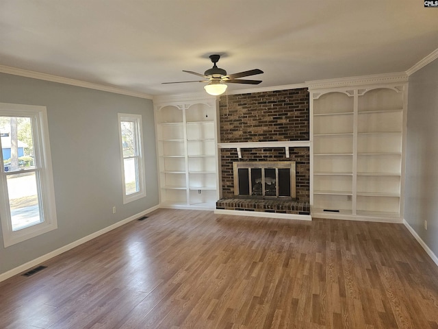 unfurnished living room featuring ornamental molding, a brick fireplace, baseboards, and wood finished floors