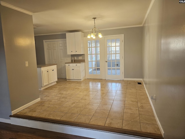 unfurnished dining area with ornamental molding, a chandelier, visible vents, and baseboards