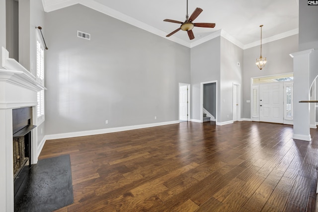 unfurnished living room with a fireplace, a high ceiling, ornamental molding, wood finished floors, and baseboards