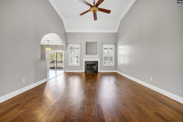 unfurnished living room with dark wood-type flooring, a wealth of natural light, a fireplace, and baseboards