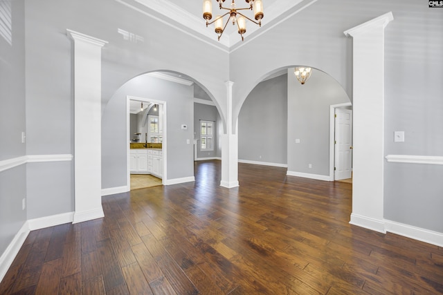 interior space with hardwood / wood-style flooring, a towering ceiling, baseboards, ornamental molding, and an inviting chandelier