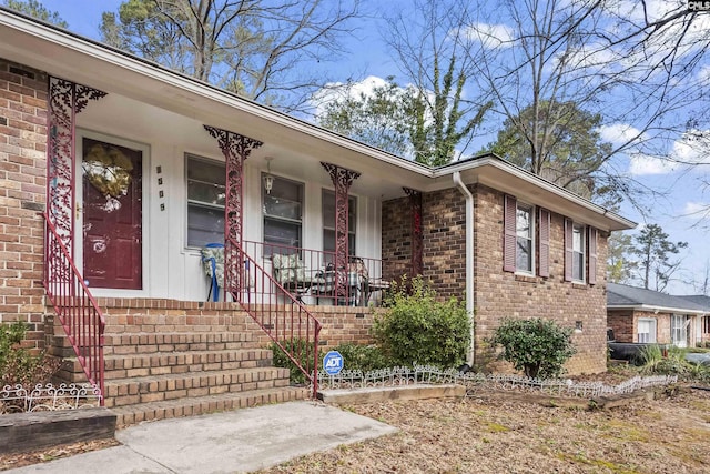 entrance to property with a porch and brick siding