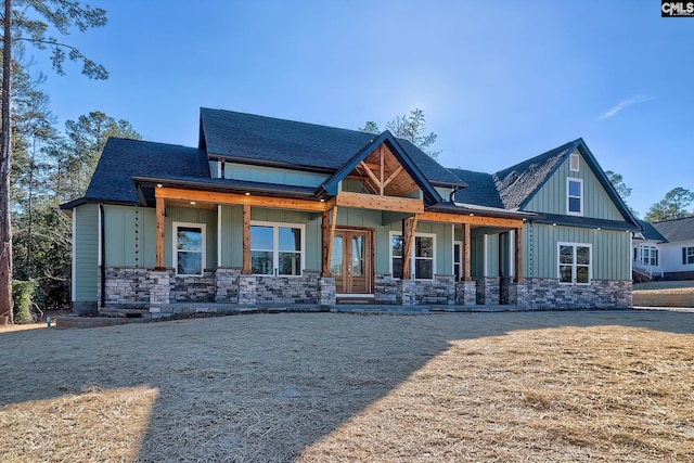 view of front of home featuring board and batten siding, stone siding, roof with shingles, and french doors