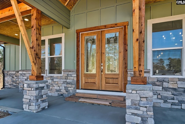 entrance to property with board and batten siding, stone siding, and a porch