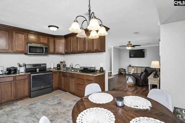 kitchen with ceiling fan with notable chandelier, stainless steel appliances, stone counters, and a sink