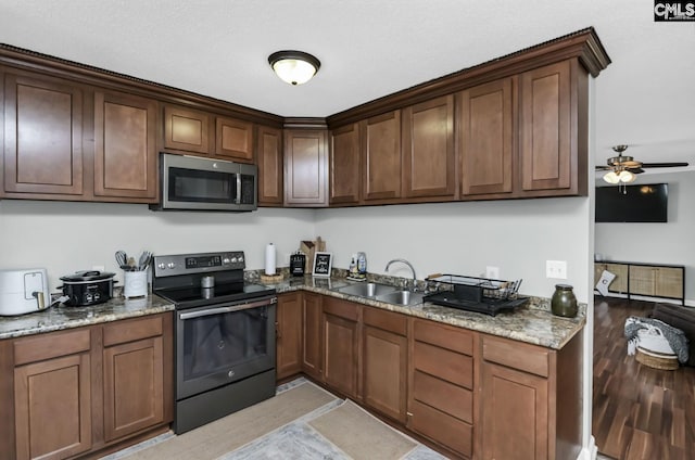 kitchen featuring ceiling fan, stone countertops, a sink, black electric range, and stainless steel microwave