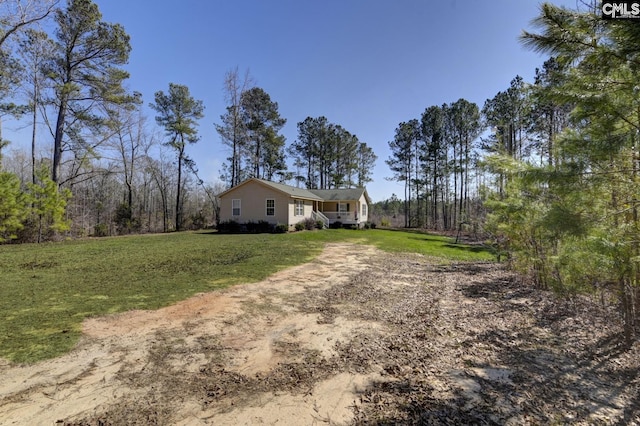 view of yard with covered porch and dirt driveway