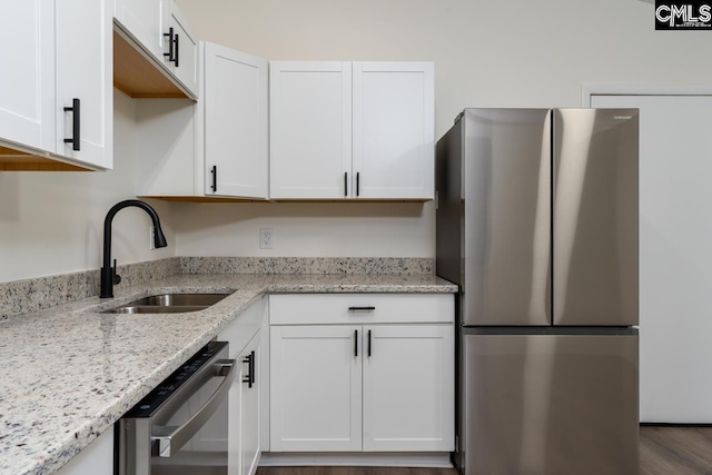 kitchen featuring stainless steel appliances, a sink, and white cabinetry